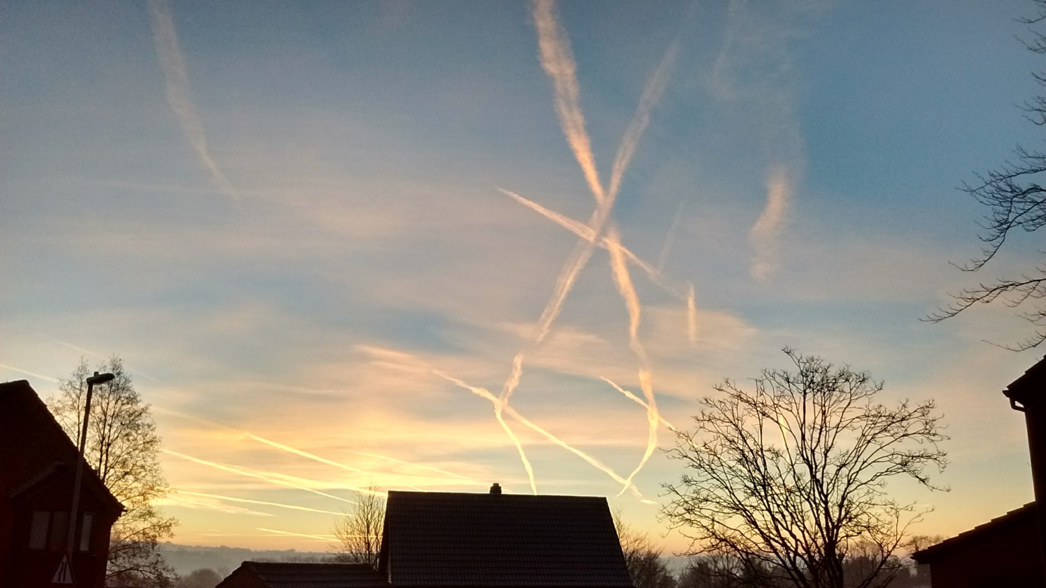Vapour trails cross the sky at sunrise in Badger Farm.