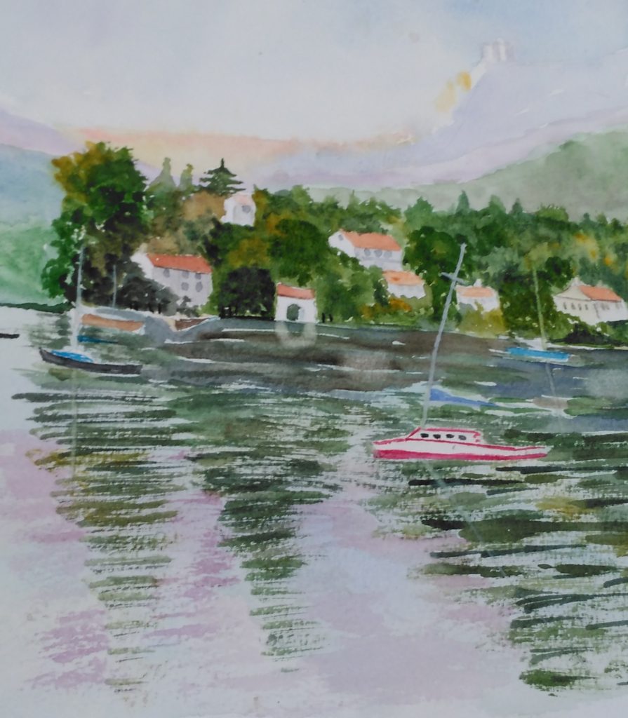 A few boats on a lake with a hillside in the background.