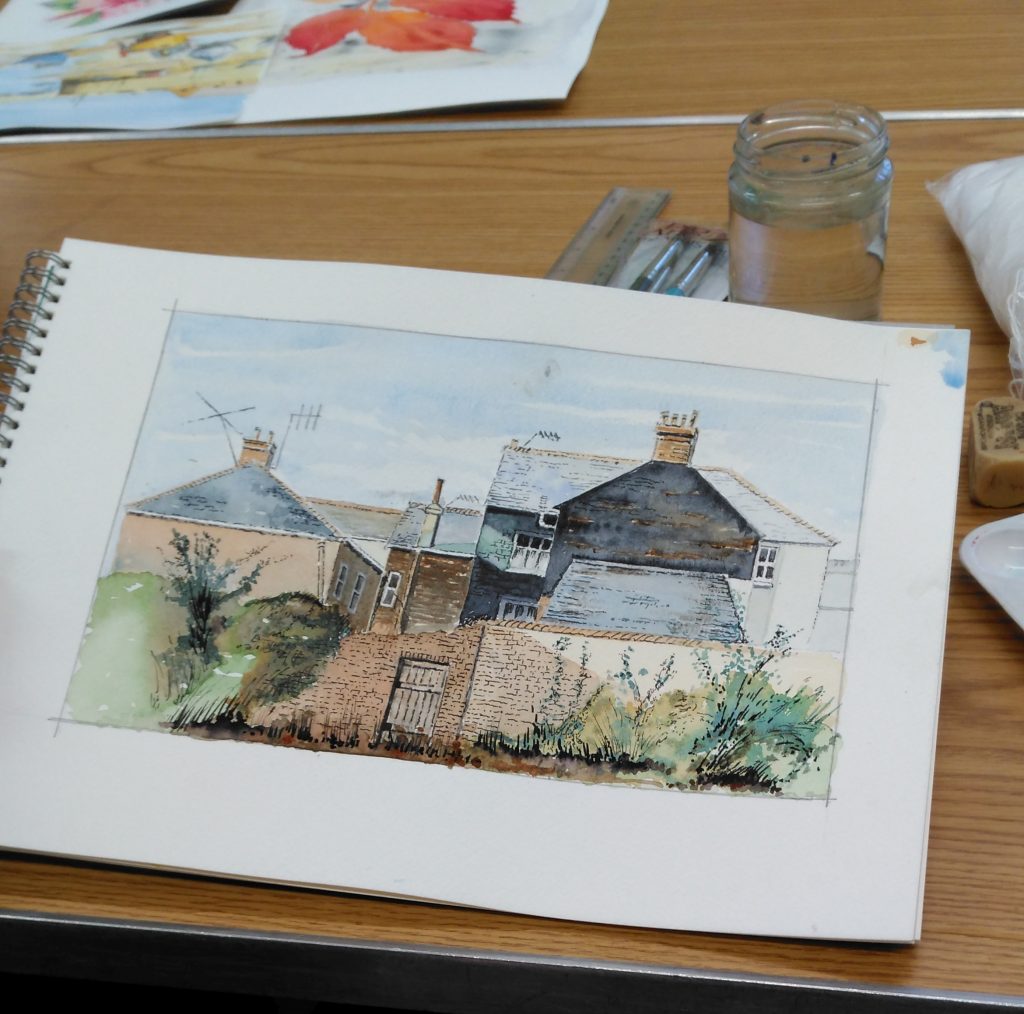 A sketch pad open to a page with a painting of terraced houses.
