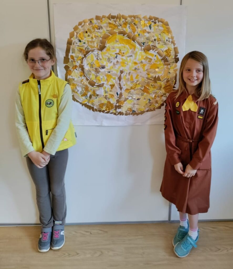 Two Brownies, one wearing the modern uniform and the other in a uniform from 50 years ago.