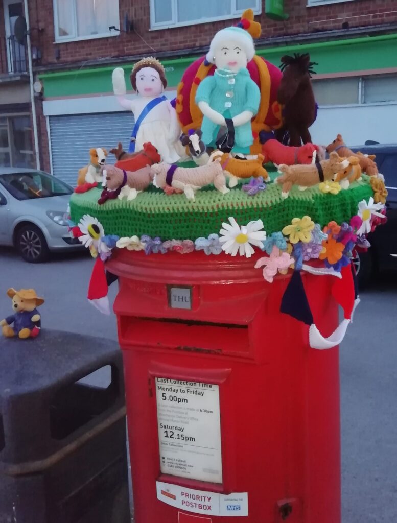 A yarn bomb on Oliver's Battery post box featuring the Queen and her corgis