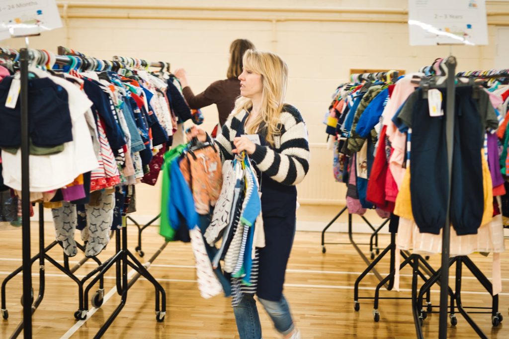 A person hanging clothes on rails at the Winchester NCT Nearly New Sale