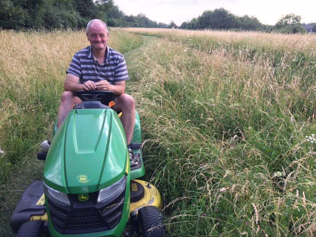 A man on a mower cutting the grass on Whiteshute Ridge in Winchester